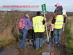 Mother with empty buggy deals with the mud, while child gets lift on steward's shoulder