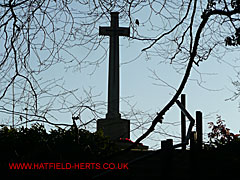 Cross at Hatfield Park War Cemetery seen through bare tree branches